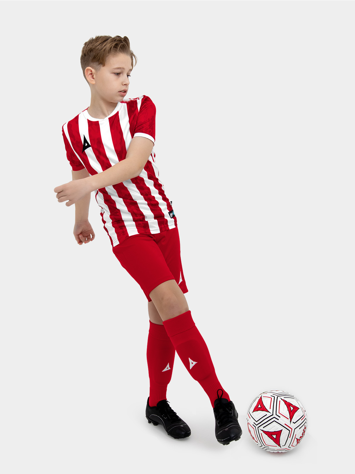 	a kids football kit in red and white with stripes and matching red shorts and socks