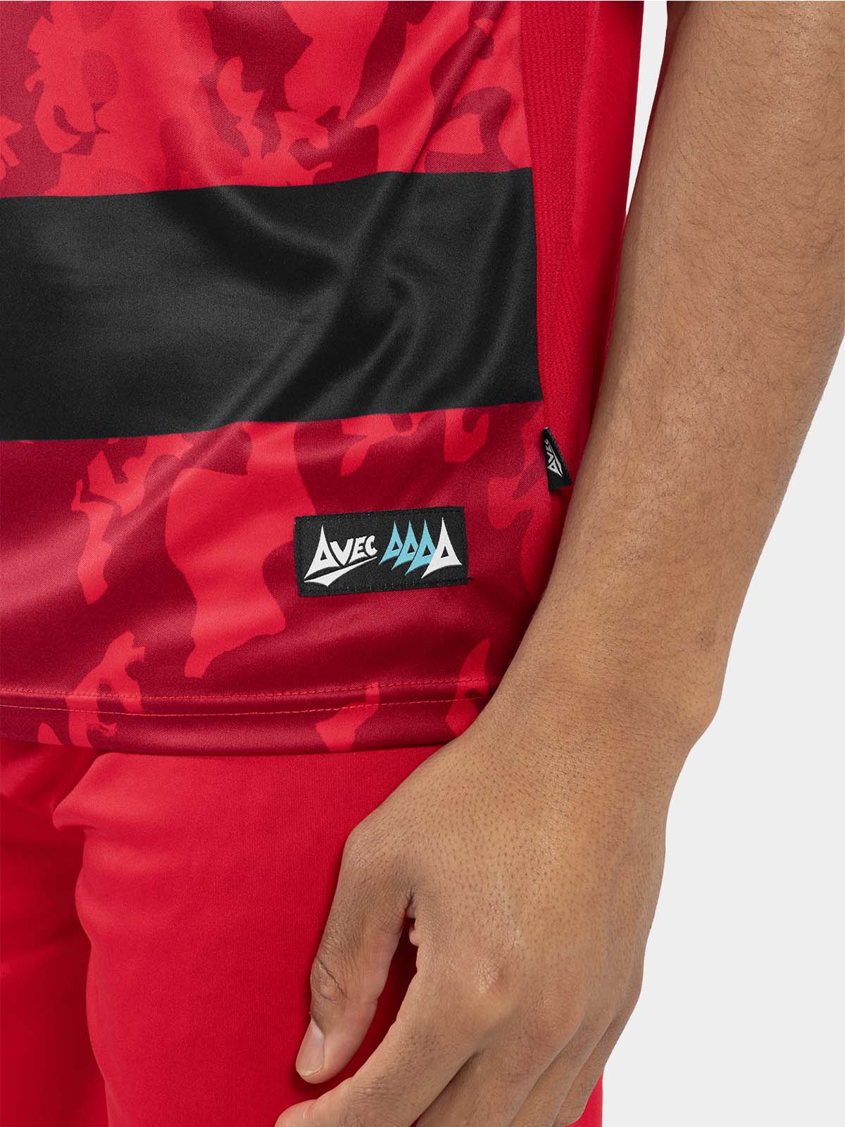	side hem view of the red and black jersey, showing the official authenticity label and moisture-wicking mesh.
